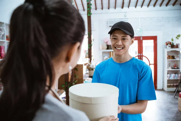 Retrato mensajero sonriente traer el paquete para la joven tendero — Foto de Stock