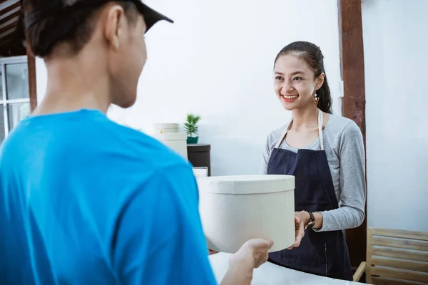 Correio retrato sorrindo trazer o pacote para jovem lojista — Fotografia de Stock