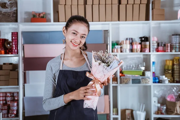 Jovem feliz trabalhando na loja de flores vestindo avental — Fotografia de Stock