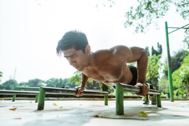 Kaslı bir adam göğüs kaslarını çalıştırmak için hareket ettiriyor.