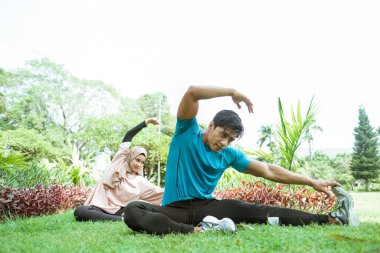 Müslüman çiftler dışarıda egzersiz yaparken bacak kaslarını çalıştırmak için hareket ediyorlar.