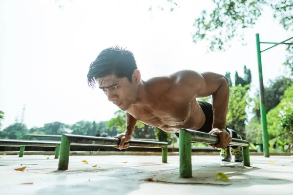 Een gespierde man doet push-up beweging om de borstspieren te trainen — Stockfoto