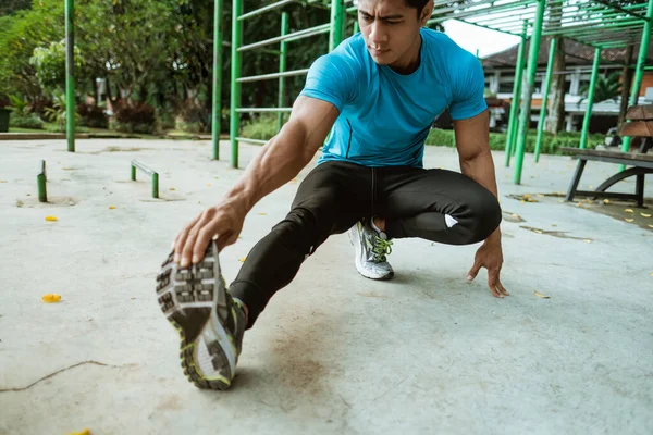 Mężczyzna w odzieży sportowej wykonuje rozciąganie nóg przed treningiem — Zdjęcie stockowe