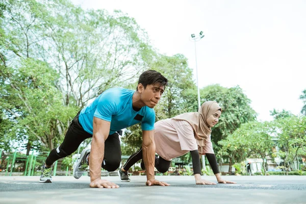 Un hombre joven y una chica en un pañuelo para la cabeza haciendo movimientos musculares abdominales juntos —  Fotos de Stock