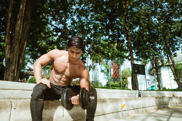 Maço adam pazılarını kopyalamak için dambıl kullanıyor.