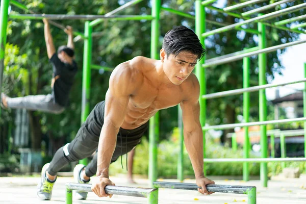 Hombre musculoso sexy haciendo movimiento push up muestra sus brazos musculares al hacer ejercicio al aire libre —  Fotos de Stock