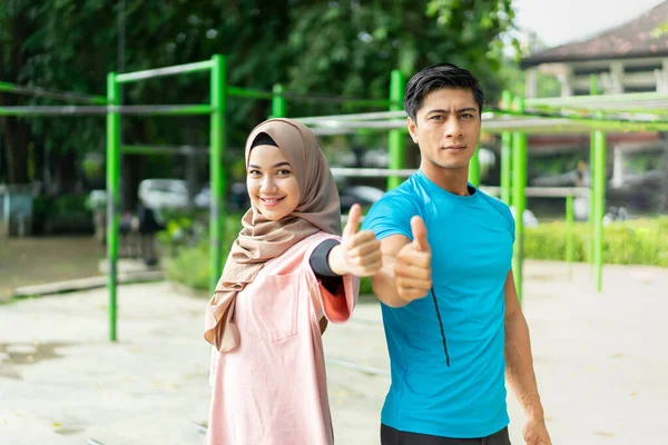 Мусульманські пари відстають від тренувань у парку, які показують пальцем вгору. — стокове фото