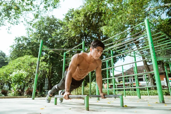 Sexy muscular homem fazendo empurrar para cima movimento mostra seu muscular braços — Fotografia de Stock