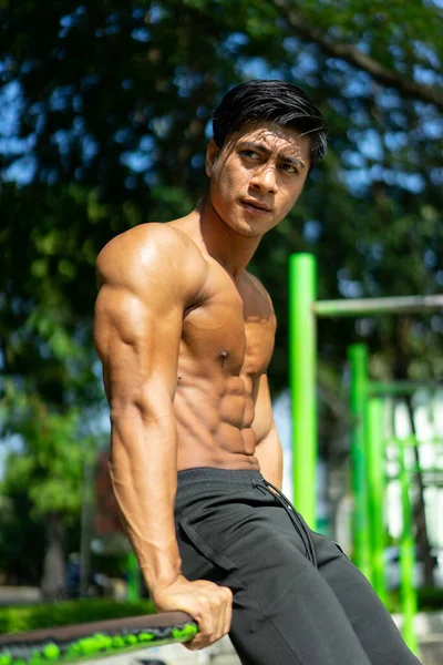 Sexy homem muscular com uma postura sentada e braços musculares visíveis quando sentado — Fotografia de Stock