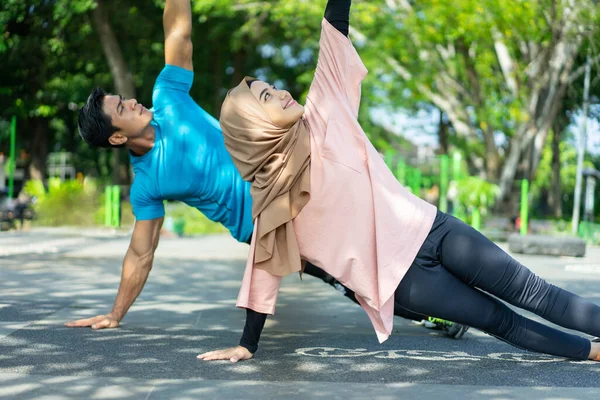 Un homme et une fille dans un voile en vêtements de gymnastique faisant des exercices de la main — Photo