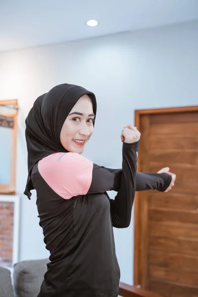 スポーツ服を着た笑顔のムスリム女性が一方を手で持ち、一方を側面に引っ張る — ストック写真