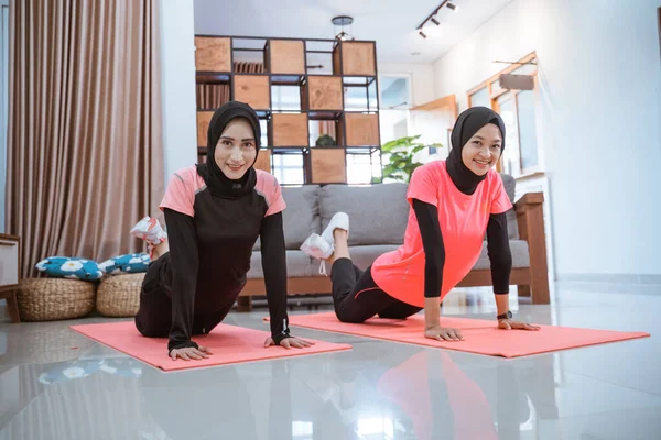 Dos mujeres usando hijab sportswear sonrisa mientras haciendo empujar hacia arriba —  Fotos de Stock