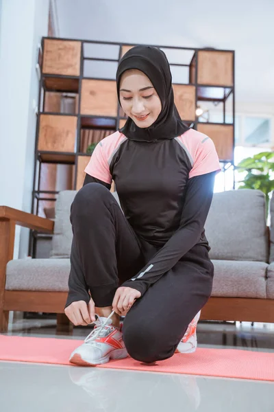 Muslimka ve svém sportovním oblečení dřepí a opravuje si tkaničky — Stock fotografie