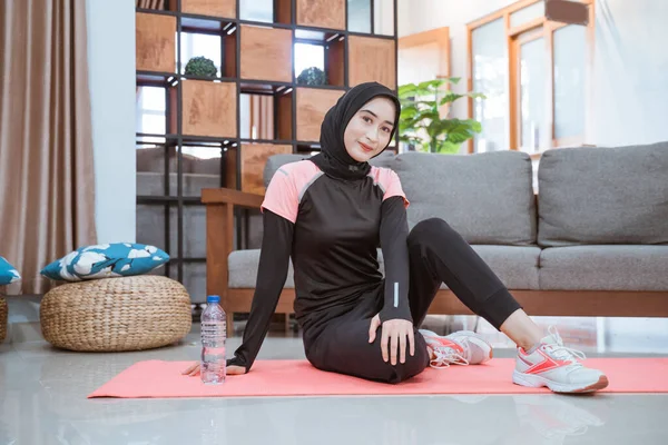 Una mujer joven con un traje de entrenamiento hijab se pone en