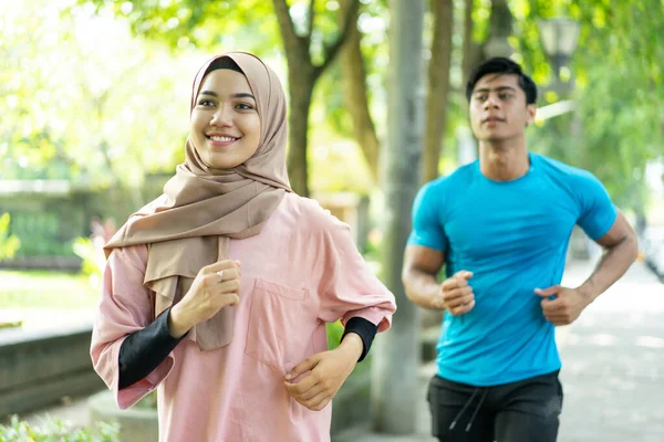 Мусульманські пари роблять біг разом, коли вправу на відкритому повітрі — стокове фото