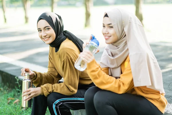 2人のベールの少女が一緒にアウトドアスポーツをした後ボトルで水を飲むのを楽しむ — ストック写真