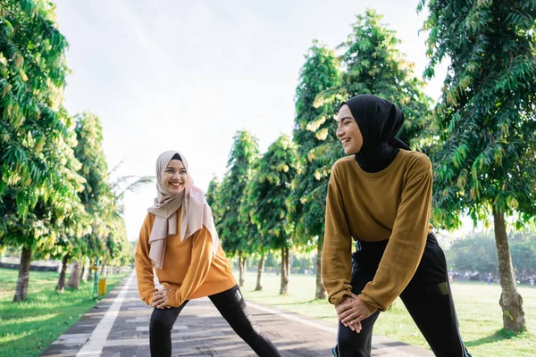 Twee gelukkig moslim meisjes in hoofddoeken doen lunges voor joggen — Stockfoto