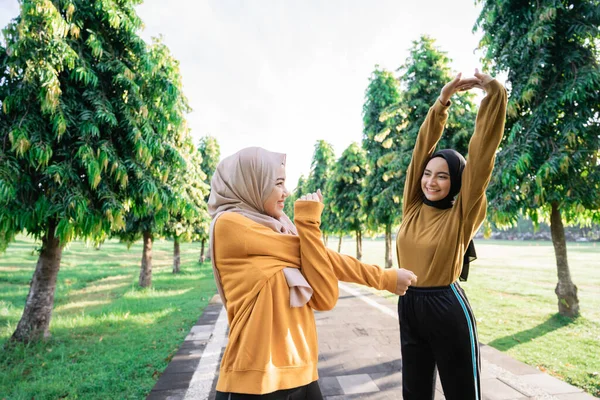 Dua gadis dengan kerudung melakukan peregangan tangan sambil bersiap-siap sebelum latihan — Stok Foto