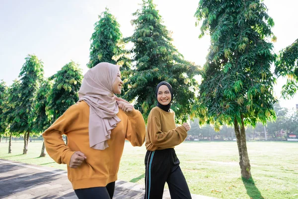Två flickor i slöja göra utomhus sport samtidigt jogga tillsammans — Stockfoto