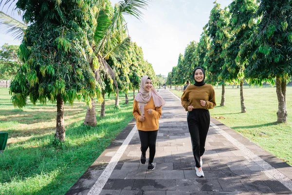 Deux filles musulmanes heureuses en foulards font du sport en plein air tout en faisant du jogging ensemble — Photo