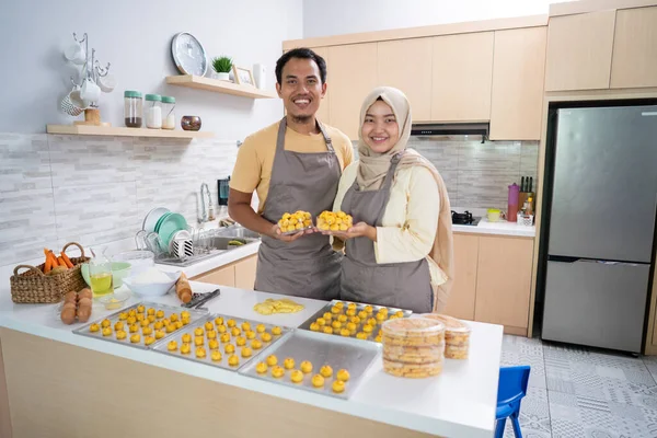 Мусульманские мужчина и женщина с подносом для выпечки настар закуски глядя на камеру улыбаясь — стоковое фото