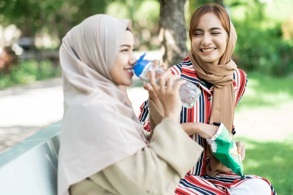 Jeune femme musulmane avec un ami profiter de leur collation tout en se relaxant dans le parc — Photo
