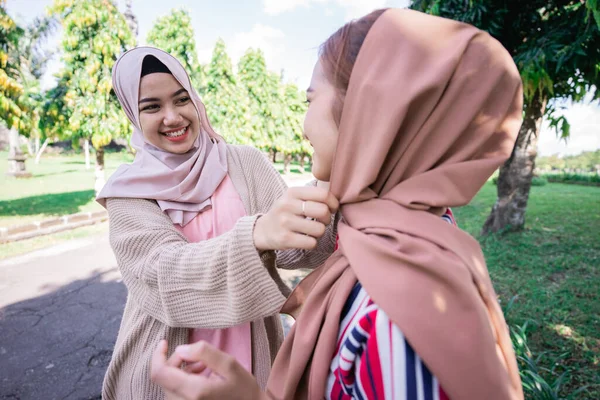 Muslim asian woman fixing friend hijab while meeting outdoor — Stock Photo, Image