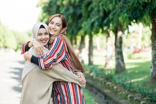 Mulheres muçulmanas em hijabs ao ar livre no dia ensolarado com amigo feliz — Fotografia de Stock