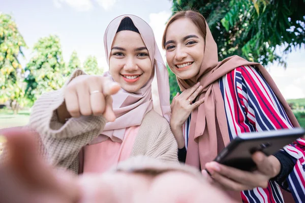 Moslim vrouw in hoofddoek ontmoeten vrienden en met behulp van de telefoon in het park — Stockfoto