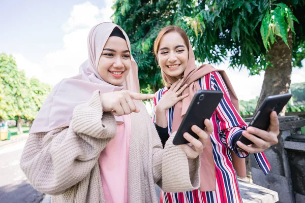 Мусульманка в платке встречается с друзьями и пользуется телефоном в парке — стоковое фото
