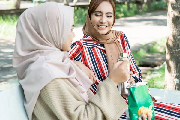 公園でリラックスしながらお友達と一緒にお菓子を楽しむイスラム教徒の若い女性 — ストック写真
