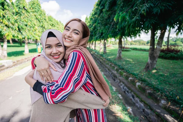 Due ragazze si abbracciano sul marciapiede. Sentirsi gioiosi e felici insieme. — Foto Stock