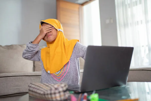 Νεαρό παιδί καλύπτει τα μάτια της, ενώ χρησιμοποιώντας φορητό υπολογιστή — Φωτογραφία Αρχείου
