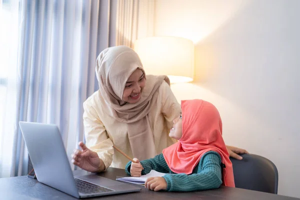 Madre ayudar a su hija a aprender en línea usando el ordenador portátil que estudia desde casa —  Fotos de Stock