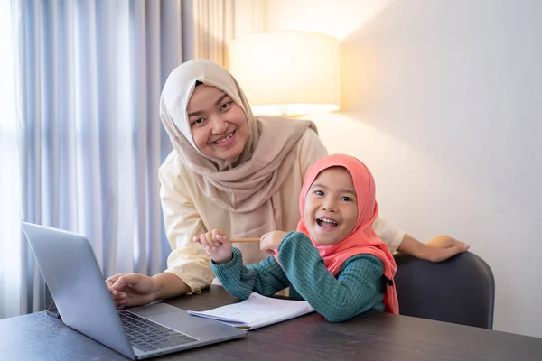 Madre ayudar a su hija a aprender en línea usando el ordenador portátil que estudia desde casa — Foto de Stock