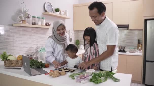 Família muçulmana com duas crianças cozinhando juntas em casa se preparando para o jantar iftar — Vídeo de Stock