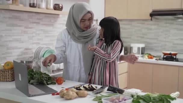 Весела жінка з хіджабом і дитиною готує вечерю разом — стокове відео