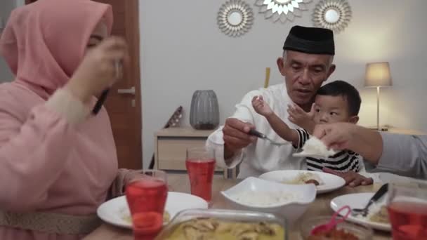 Muslim asia dengan hijab makan malam iftar bersama di rumah duduk di meja makan — Stok Video