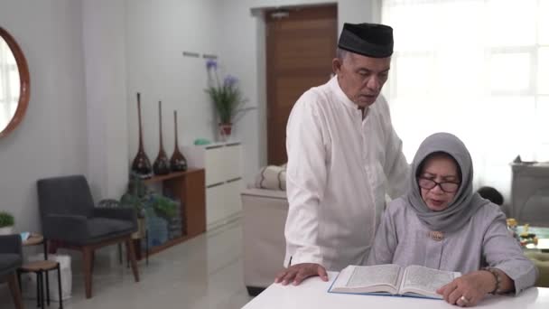 Muslim senior man teaching wife reading Koran or Quran in living room — Stock Video