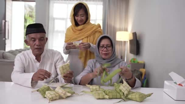 Pareja musulmana e hija haciendo ketupat para eid fitr mubarak celebración en casa — Vídeos de Stock