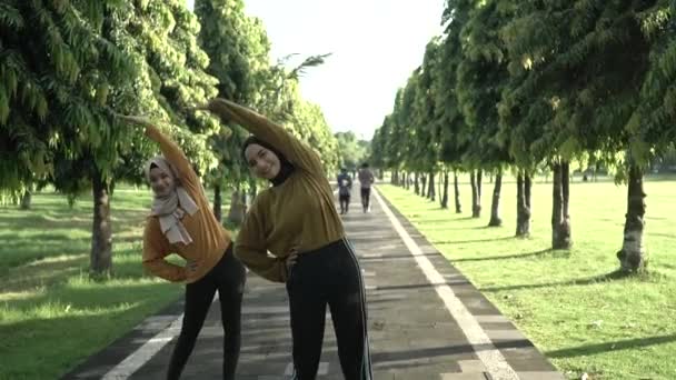 Dwie zasłonięte muzułmanki wyciągają ręce przed joggingiem i sportem na świeżym powietrzu — Wideo stockowe