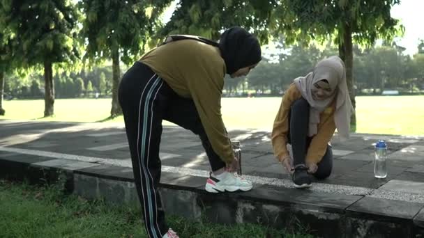 Duas meninas em capuzes de agachamento ajustando seus atacadores como eles se preparam antes de se exercitar — Vídeo de Stock