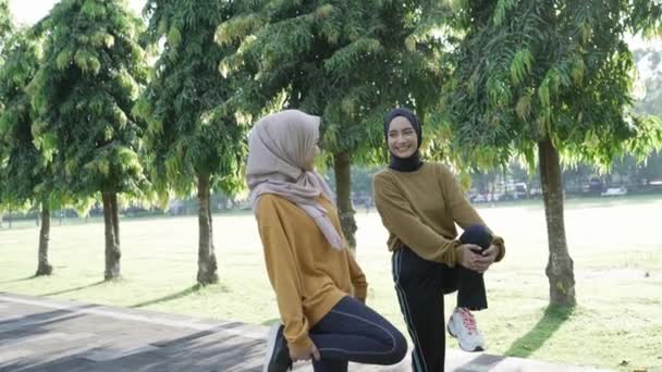 Two Muslim girls in headscarves stretch their muscles by raising their hands to exercise outside the room — Stock Video