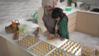 Ramazan etkinliği sırasında Müslüman anne kızıyla birlikte nastar pastası yapıyor.
