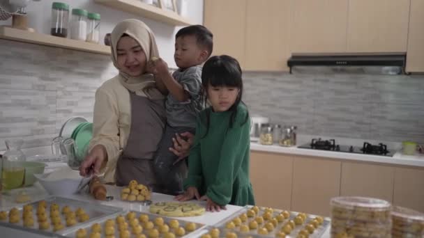 Μια νεαρή μουσουλμάνα με δύο παιδιά που μαγειρεύουν μαζί στην κουζίνα. — Αρχείο Βίντεο