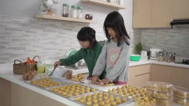 İki küçük kız birlikte nastar tart keki yapıyorlar.