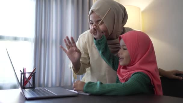 Madre y su hija saludan su mano a la computadora portátil durante la reunión de clase — Vídeo de stock