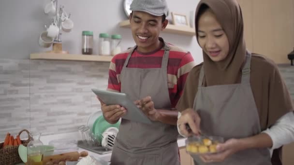 Muslim pasangan dengan tablet pc memanggang kue untuk dijual selama ramadan — Stok Video