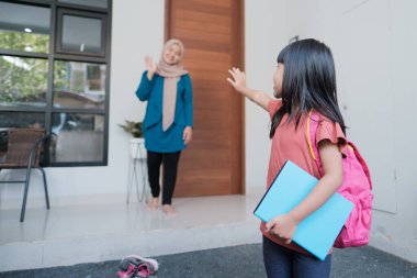 Mutlu çocuk okula gitmeden önce annesine el sallıyor.