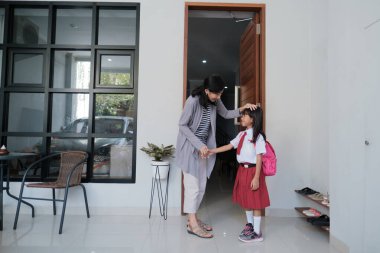 Okula dönelim. İlkokul üniformalı Asyalı öğrenci okula hazırlanıyor.